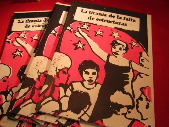 Es una serigrafia con fucsia fluor y negro que muestra un grupo de personas reunidas y una en el medio ocupando aparentemente la palabra y el espacio, rodeada de estrellas.